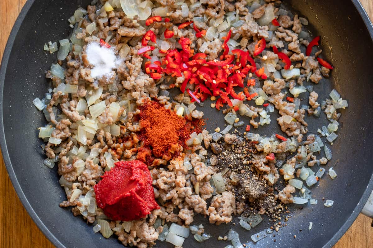 adding the spices and the tomato paste to sautéed onions and mince
