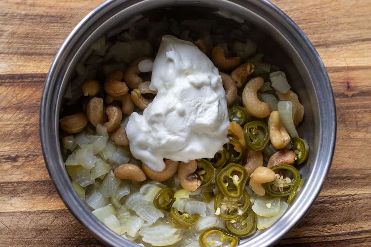 yogurt is added to cooked onions, chili, and cashew nuts