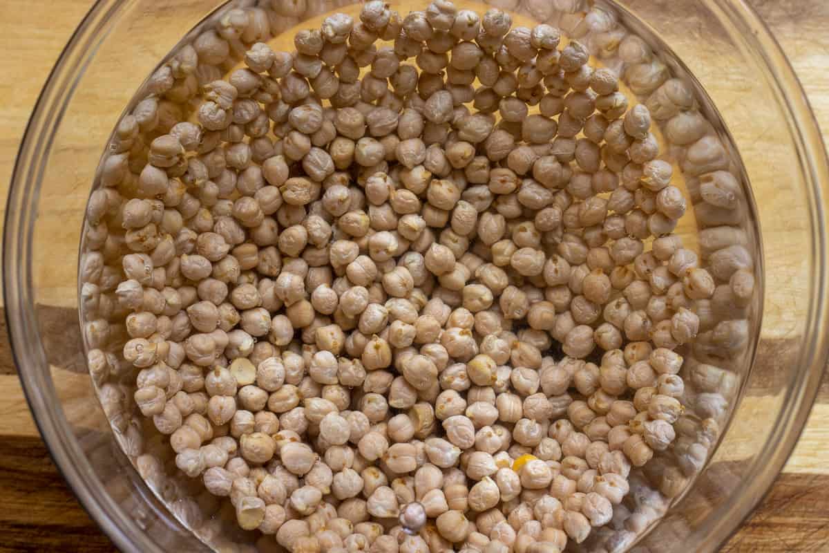 the glass bowl with chickpeas is filled with water