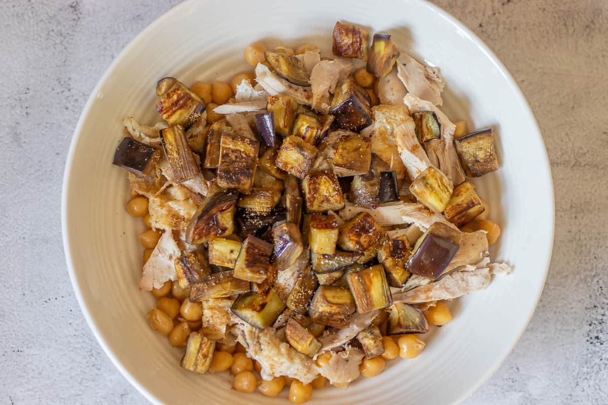 roasted eggplants are placed on top of chickpeas and chicken