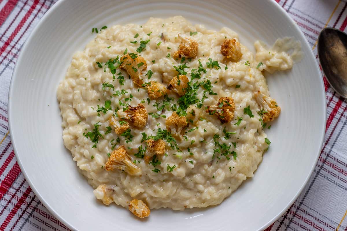 creamy cauliflower risotto served in a bowl garnished with roasted cauliflower