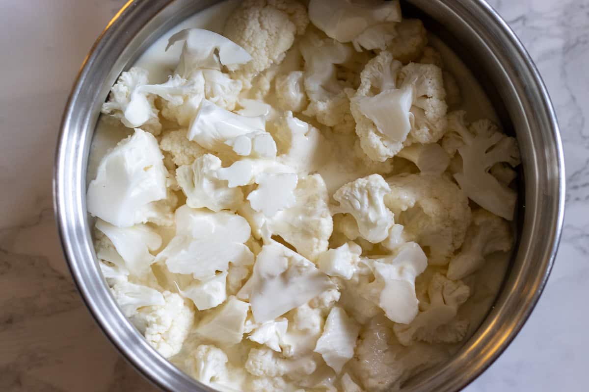 cauliflower pieces placed in a pan with milk and cream