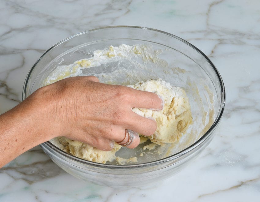 Hand kneading dough in a bowl.
