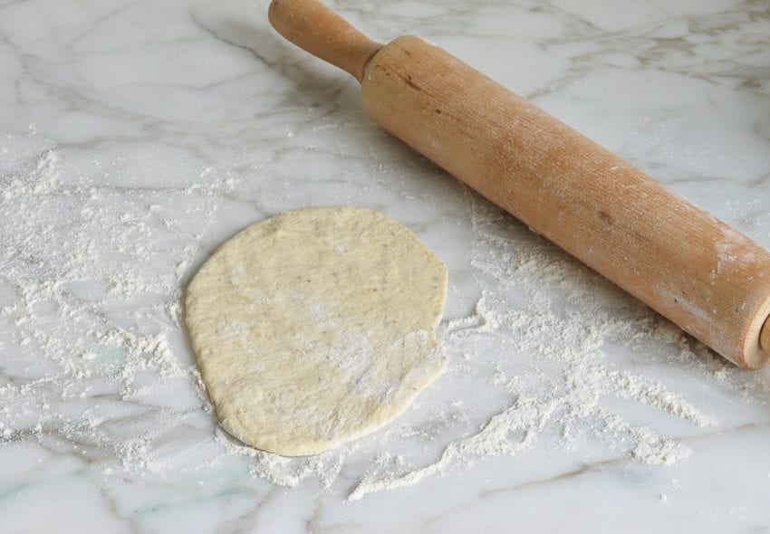 Flattened dough with a rolling pin.