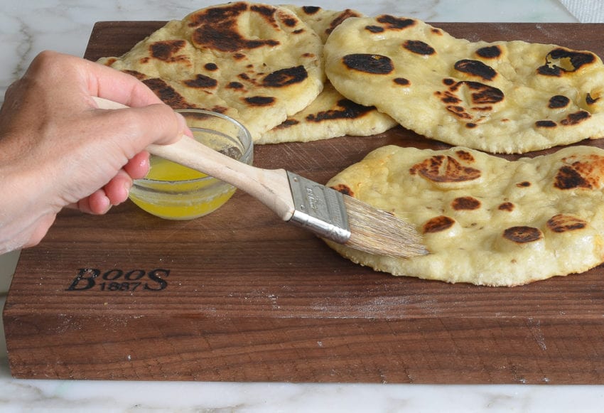 Person brushing naan with butter.