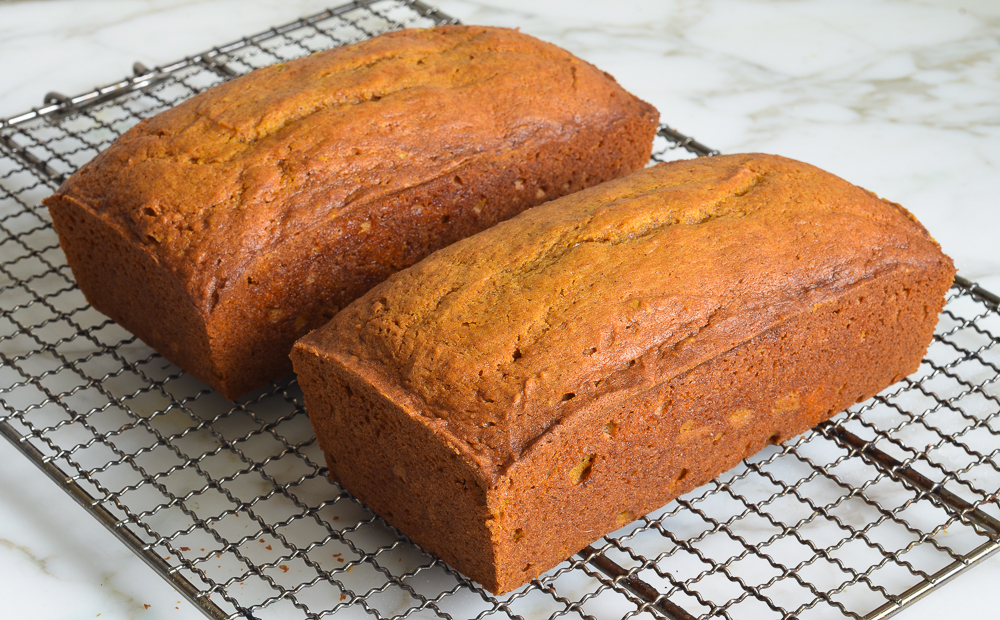 Two loaves of pumpkin bread on a wire rack.