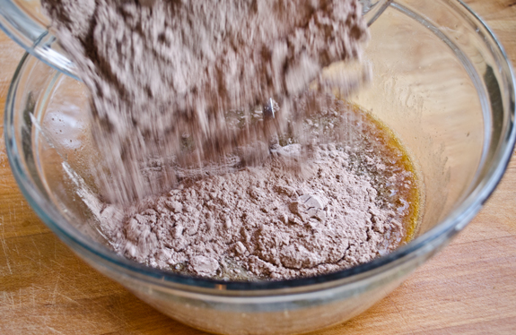 Dry ingredients pouring into a bowl of wet ingredients.